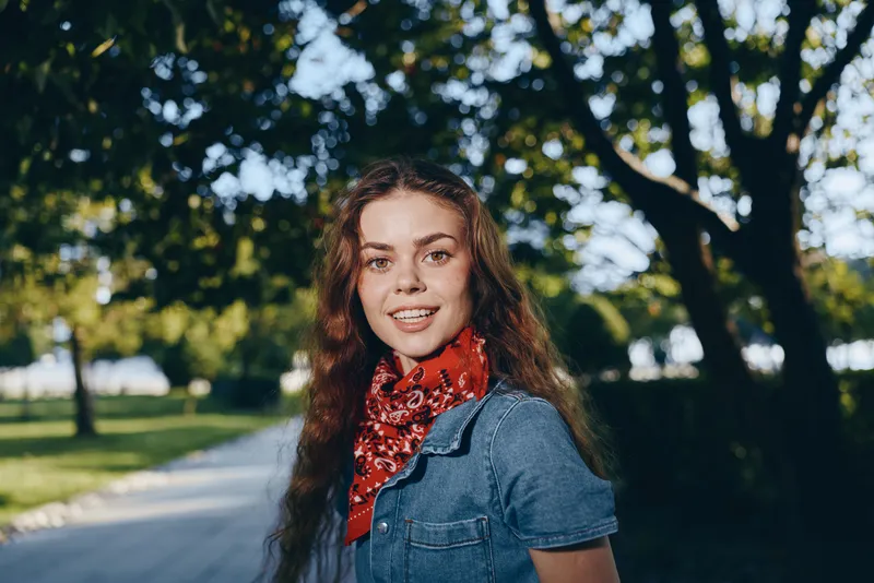 Lifestyle woman with modern boho-western denim street style smiling outdoors in natural sunlight with film color tones and casual confident mood.