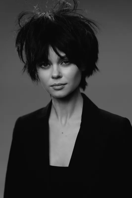 Black and white portrait of a woman with short dark hair wearing a dark jacket looking confident and calm