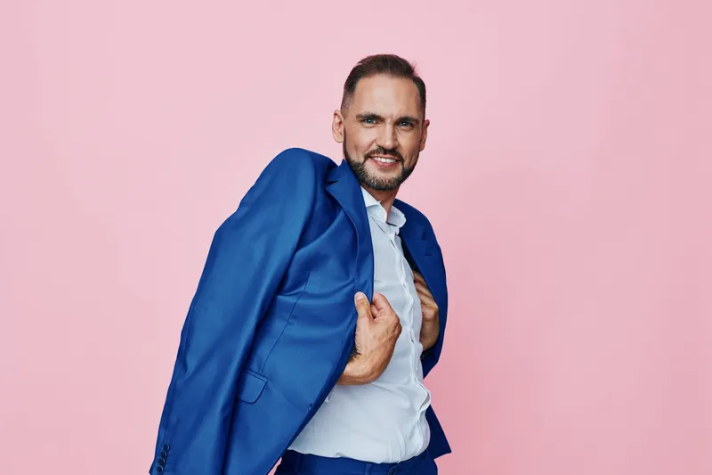 Professional man in a blue suit on a pink isolated background, conveying confidence, energy, and dynamic emotion suitable for business and corporate branding.