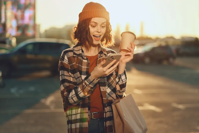 woman coffee phone shopping urban joyful candid authenticity golden moment at sunset, a mindful living street portrait with golden hour glow, relaxed outfit and emotional storytelling captured vividly