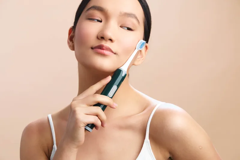 Asian woman enjoys a refreshing morning routine, holding a toothbrush in a bright, clean bathroom. She gazes contentedly, conveying freshness and confident selfcare.
