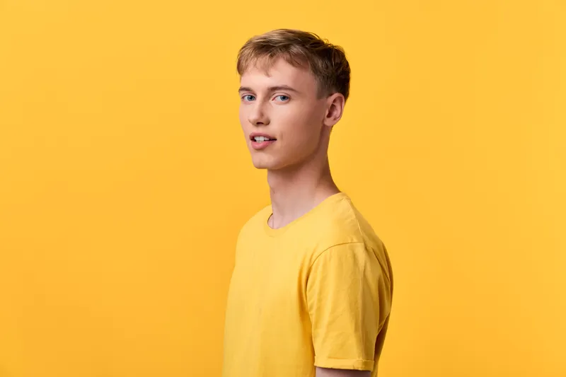 Male in a yellow shirt stands against a bright yellow studio background, relaxed pose, clean composition, soft lighting creating a vivid, cohesive color mood for fashion or lifestyle stock