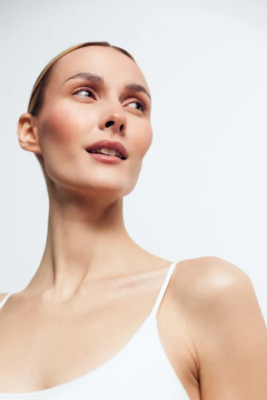 Woman with headband in close up portrait, skincare beauty wellness and self care theme, shoulders against white background, soft light studio mood, calm expression