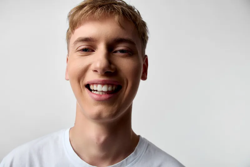 Smiling man with short blond hair wearing a white shirt, close up, friendly and confident, capturing a casual, bright and approachable mood