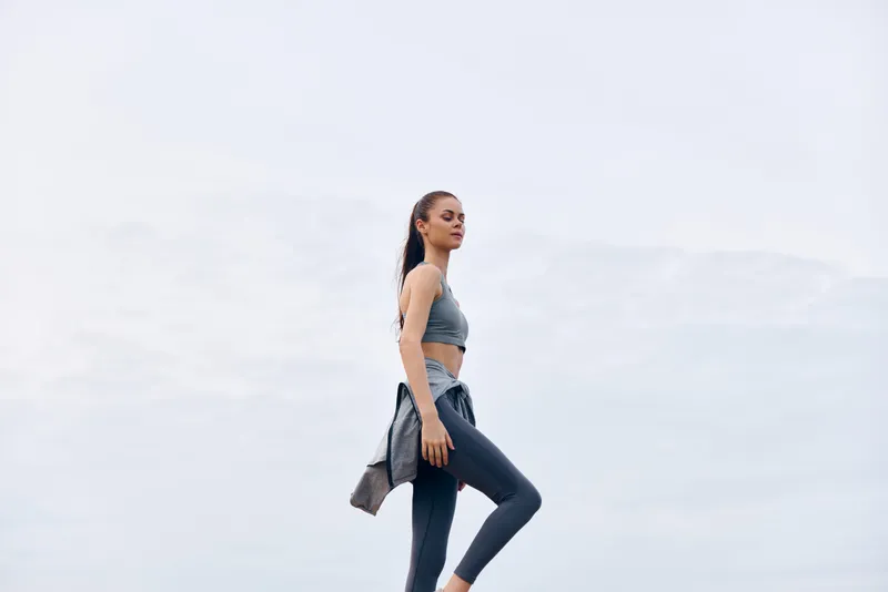 Young fitness woman in athletic clothing walking outdoors, showcasing confidence and a healthy lifestyle, perfect for healthy living concepts