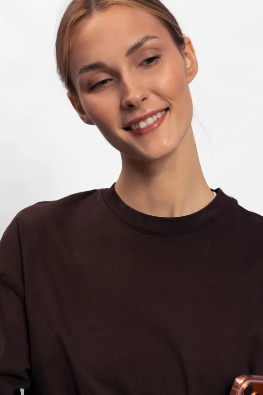 Smiling young woman with clear skin wearing a dark top looks down with a gentle happy expression. Studio portrait with soft lighting on white background. Concept of beauty and positivity.