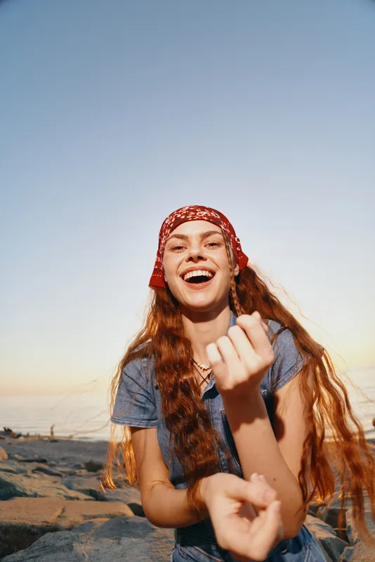 Lifestyle woman in modern boho-western denim street style smiling brightly outdoors with natural light and film color tones creating a fresh, carefree summer vibe