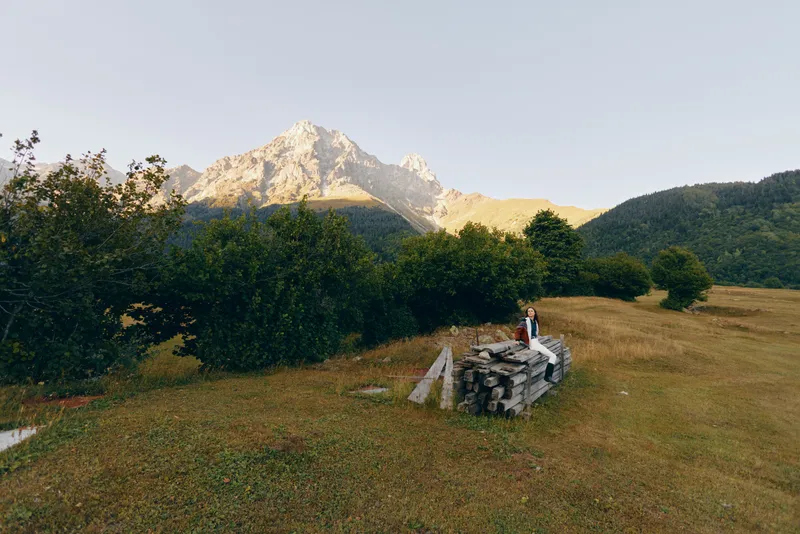 Mountain meadow couple standing on stone ruins in a scenic landscape, nature and outdoors travel scene with trees, grassy field and distant peak, romantic hiking moment.