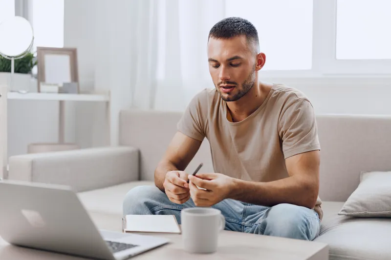 Thoughtful man engaging in creative brainstorming while sitting in a cozy living room, dressed casually, surrounded by natural light and modern decor.