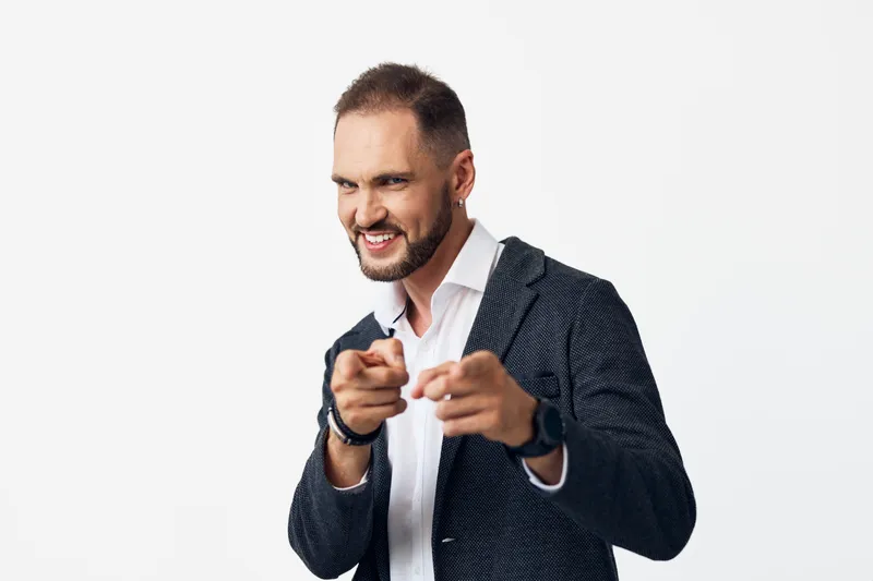 A confident business professional man on an isolated colorful backdrop, smiling and pointing at the camera, conveying motivation, leadership, and a dynamic, optimistic workplace presence.