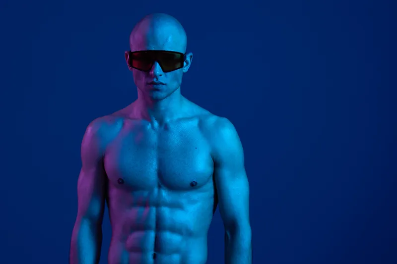 A muscular man posing confidently in a striking blue light, wearing stylish sunglasses. This dynamic composition emphasizes power and boldness in an artistic way.
