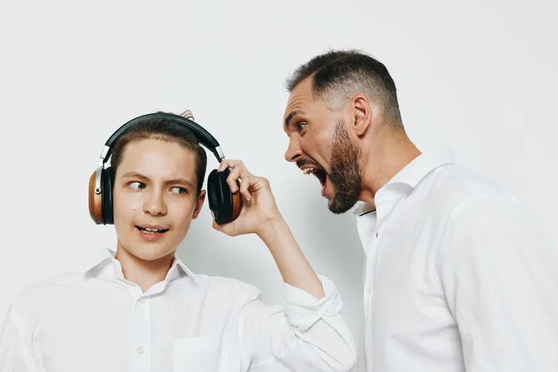 A professional businessman displays strong emotions while engaging with a younger figure against an isolated colored background, capturing intense expression, confident posture, and dynamic