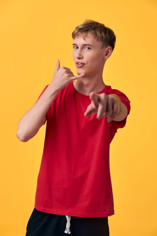 Hand gesture, call me, young man in a red shirt poses against an orange background, conveying friendly outreach, confident style and clear communication in a studio setting ready for branding