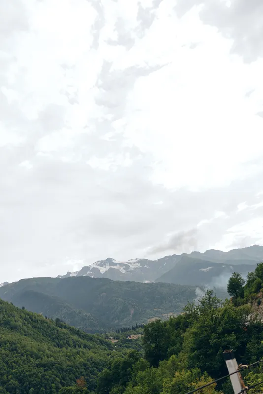 Mountain landscape with lush greenery, rolling hills and a cloudy sky, creating a tranquil outdoor scene perfect for nature travel and scenery photography.