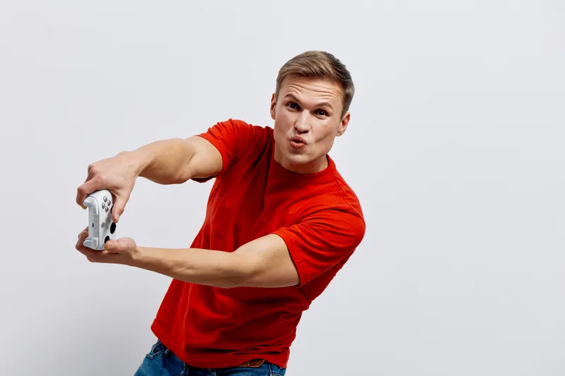 young caucasian man in red tshirt excited play video game hold remote controller isolated on white background casual lifestyle digital detox concept