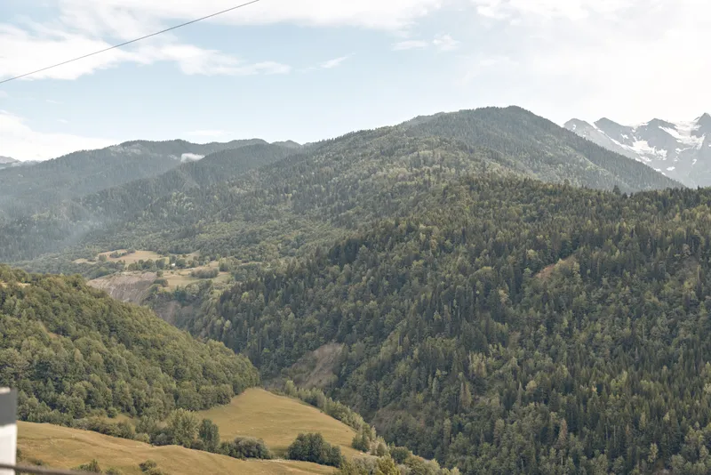 Mountains and valley stretch across a tranquil outdoor landscape, with forested ridges under a clear blue sky, revealing expansive natural scenery, serene wilderness, and wide open horizons.
