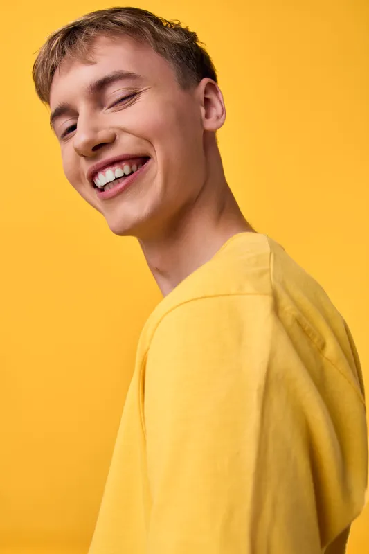 Smiling man in a yellow shirt against a vivid yellow background, capturing bright mood, casual fashion, and cheerful energy perfect for lifestyle, positivity, and optimistic branding.