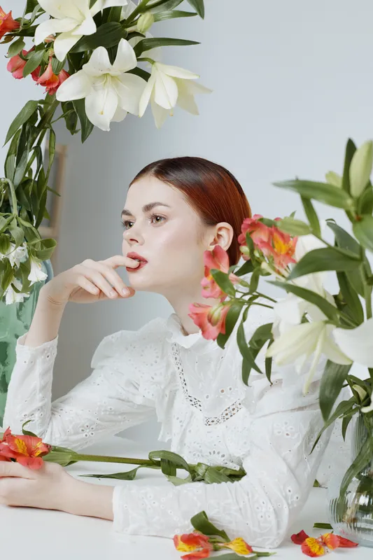 Elegant young woman with floral arrangement in bright colors, showcasing beauty and serenity in a light filled studio setting