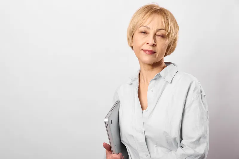 Elderly woman holding a tablet, white background, soft studio light, calm portrait, using digital technology for communication and daily life, healthcare concept, care
