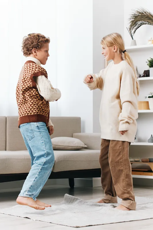 Authentic play scene featuring two children in a cozy living space, capturing a school age moment, simple fashion, and everyday lifestyle in warm daylight.
