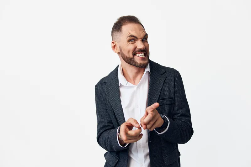 Professional business man on an isolated colored background projects confidence, with a bold smile and pointing gesture conveying leadership and motivation in a corporate setting.