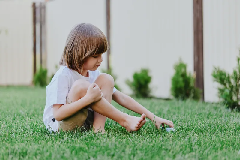 Playful boy enjoying a sunny day in the grass, exploring nature with curiosity and joy, representing childhood innocence and adventure in a vibrant outdoor setting.