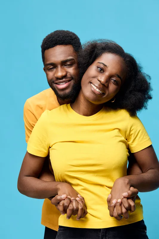 A joyful couple in matching yellow t shirts embraces against a vibrant blue background, radiating happiness and love in a modern, youthful concept