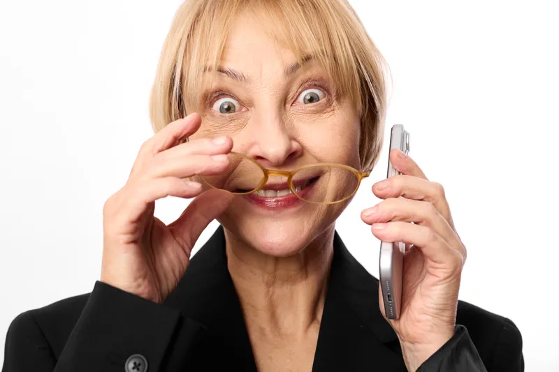 Woman, senior, phone, surprised, anxiety, stress, communication, blonde hair, hands near face, older business woman speaking on smartphone against white background