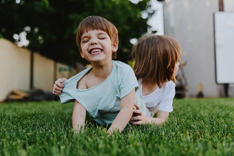 Happy children playing together on a sunny day, enjoying laughter and friendship on a green lawn, capturing the essence of childhood joy.