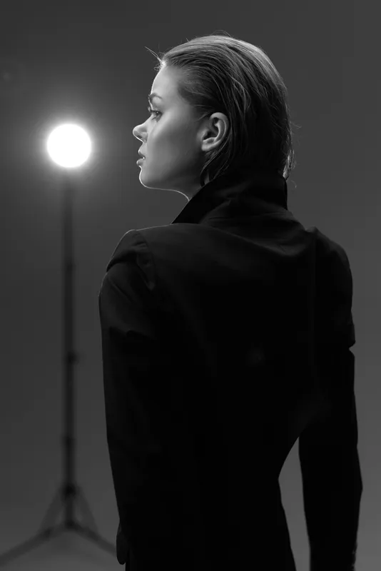 Black and white portrait of a thoughtful woman in studio lighting, showcasing elegance and introspection.