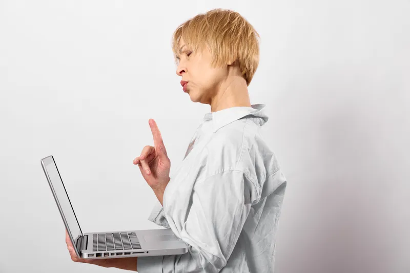 Child, laptop, technology, learning theme: a child points while hands rest on the keyboard, focused on the screen against a plain background, modern education concept.