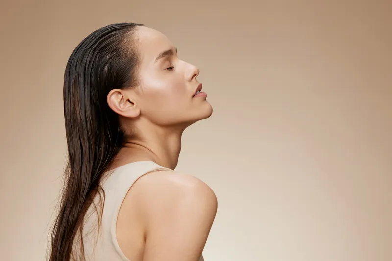 Portrait of a serene woman with long wet hair against a beige background, reflecting beauty and confidence, ideal for wellness and self care themes