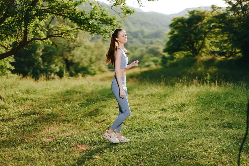 Young woman jogging in fitness wear amid green landscape, showcasing healthy lifestyle and determination, perfect for wellness and fitness themes