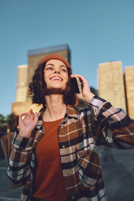 Woman phone smile urban shopping portrait during golden hour glow, a candid lifestyle moment with authenticity and mindful living, emotional storytelling in modern city streets.