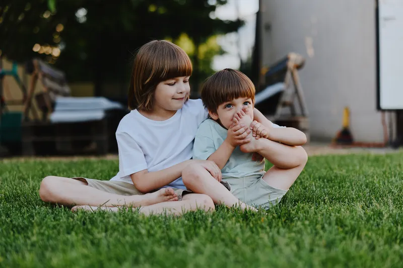 Happy children enjoying a sunny day, playing together on the grass, showing joy and connection in their carefree moments outdoors.