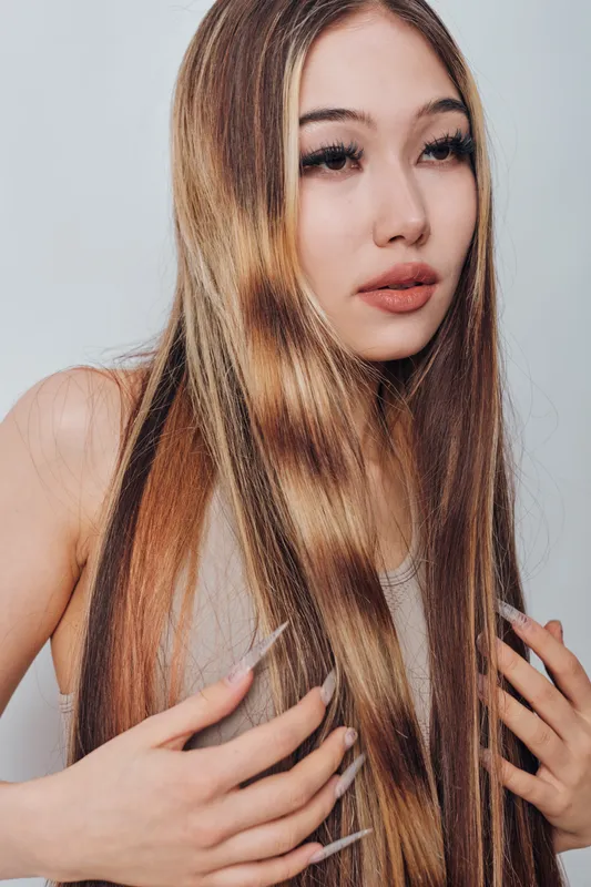 Young woman with long straight hair and natural makeup posing against plain background. Beauty portrait with focus on healthy hair and flawless skin, fashion model with gentle expression.
