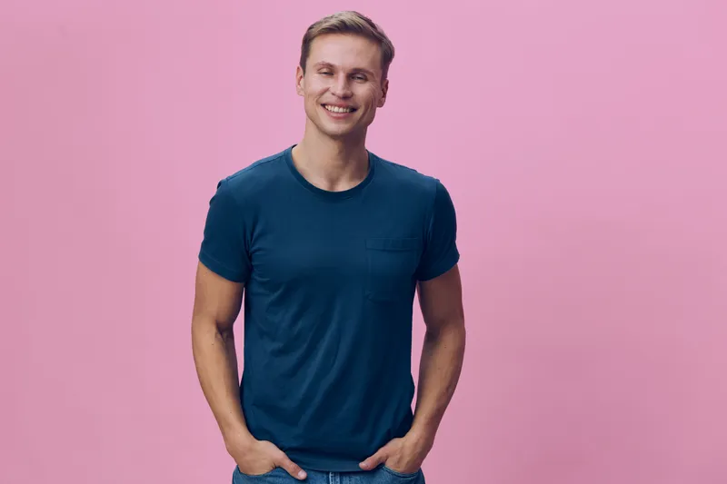 smiling young man casual tshirt look camera stand isolated pink background happy cheerful emotion digital nomad concept