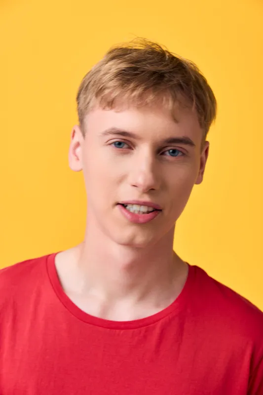 Young man casual smile red shirt yellow background close up suitable for fashion lifestyle and product showcase stock imagery with a bright approachable mood in a modern studio setting
