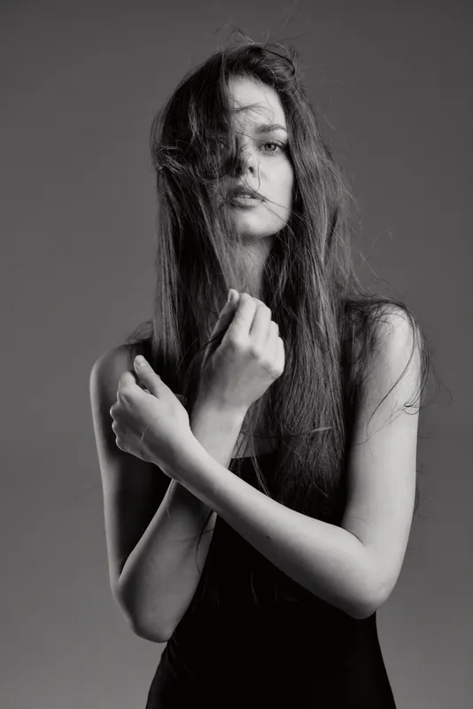 black and white portrait of a young woman with long hair and expressive eyes in a contemplative pose