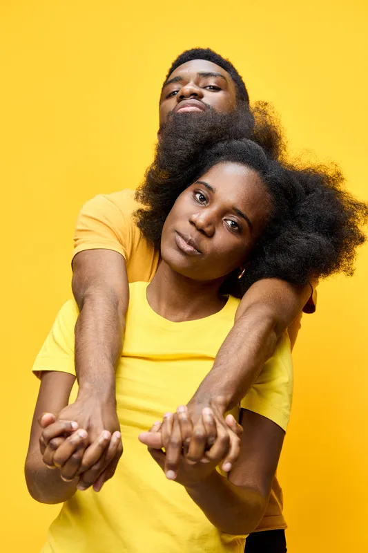 Young couple embracing with joyful expressions, wearing matching yellow t shirts against a vibrant yellow background, symbolizing love and connection
