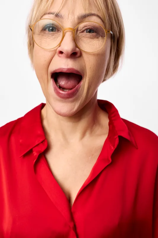 Woman surprised shock glasses portrait closeup emotion red shirt female, open mouth gasp, intense eyes, astonished reaction, white studio background, isolated headshot