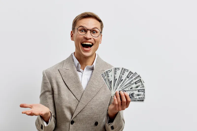 excited young caucasian man holding dollar bills wear beige jacket smile happy financial success concept isolated on white background money freelance work online earnings