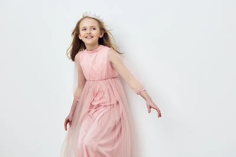 Joyful girl in pink dress with tulle, smiling, creating a playful atmosphere, suitable for children s photography and celebrations