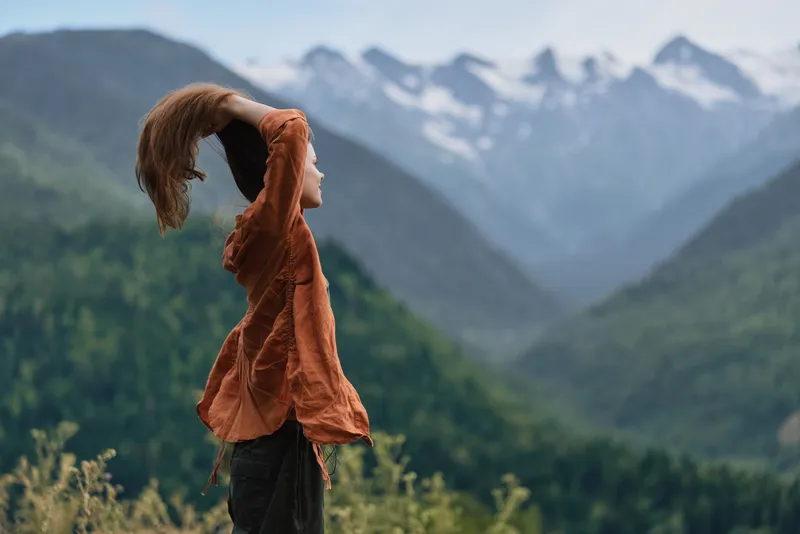 mountain landscape outdoor wind scarf woman nature scenery in open air stands gazing at distant peaks capturing a serene moment of exploration and freedom among vast rugged terrain