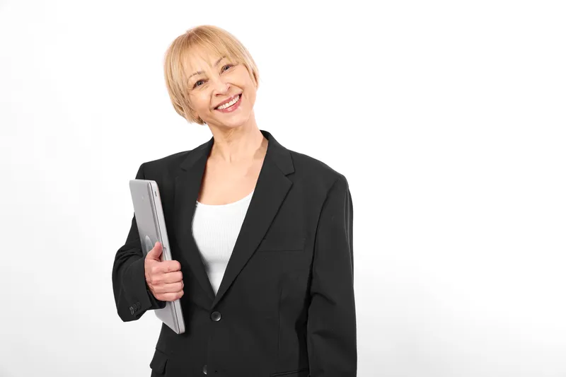 Elderly woman smiling in studio holding smartphone on white background, relaxed posture, friendly facial expression, focused on communication technology, copy space for support