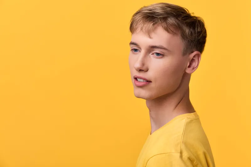 Young man with a yellow shirt under soft studio lighting against a bright yellow background, clean composition perfect for fashion and lifestyle campaigns