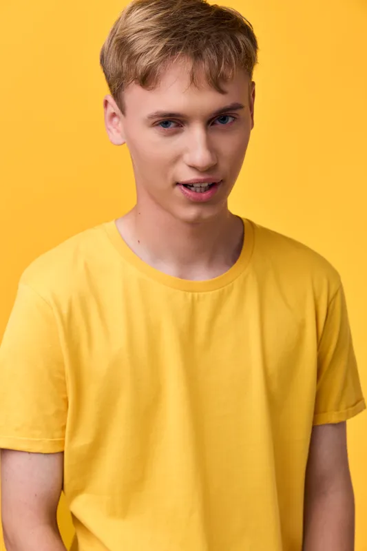 Young man, yellow shirt, yellow background, casual style, studio shot, front view, smiling, fashion model vibe for lifestyle or apparel campaigns