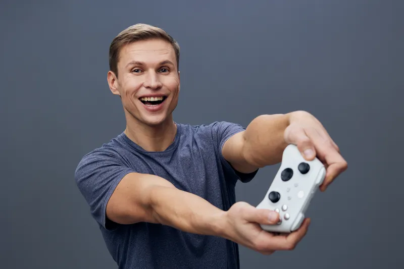 excited smiling young caucasian man hold gamepad play videogame on gray background digital entertainment technology concept