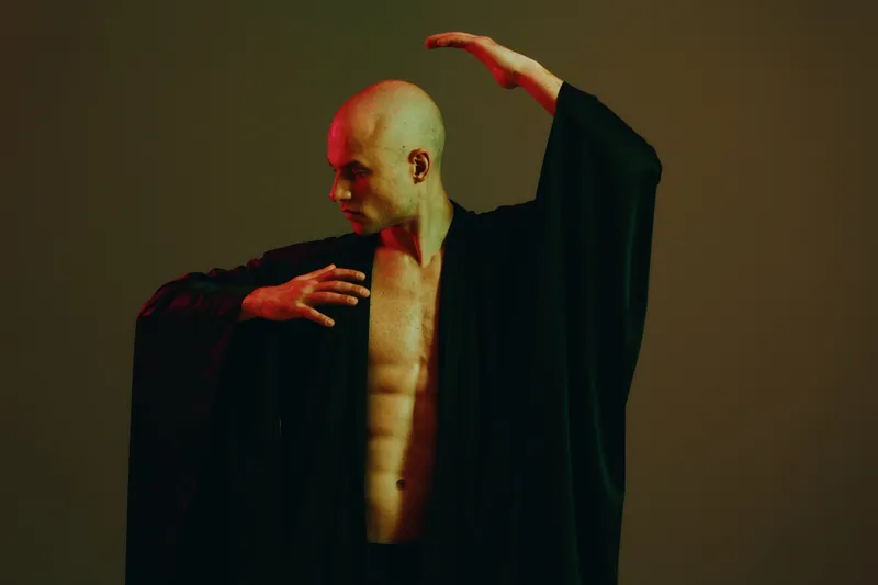 Artistic portrayal of a muscular man in a black kimono, showcasing strength and grace, with dramatic lighting emphasizing his physique and movements.