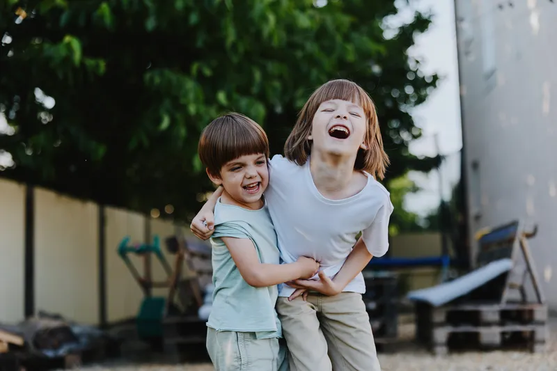 Happy children laughing together in a playful outdoor setting, enjoying carefree moments and vibrant nature.